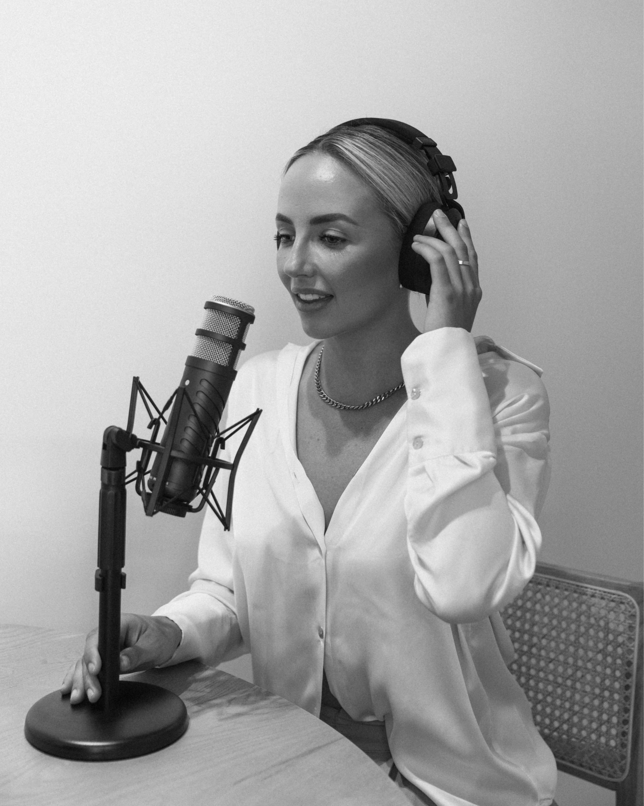 Woman wearing headphones and speaking into a desk microphone